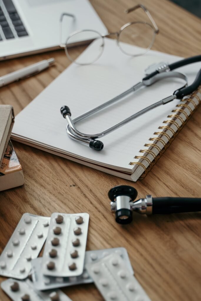 Stethoscope, pills, and notebook on a doctor's desk, showcasing a clinical setting.