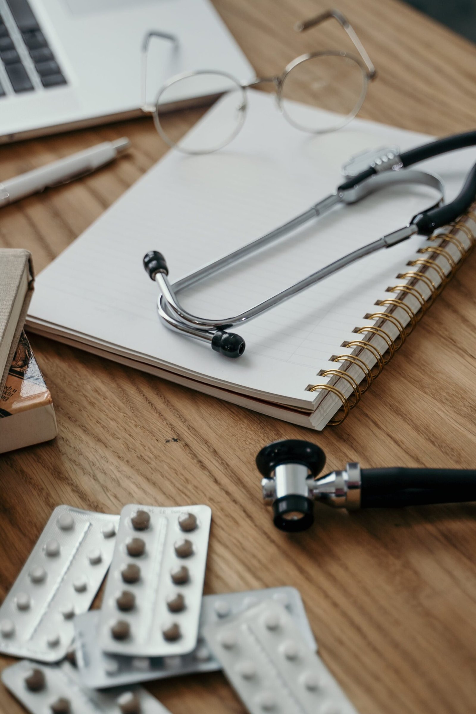 Stethoscope, pills, and notebook on a doctor's desk, showcasing a clinical setting.